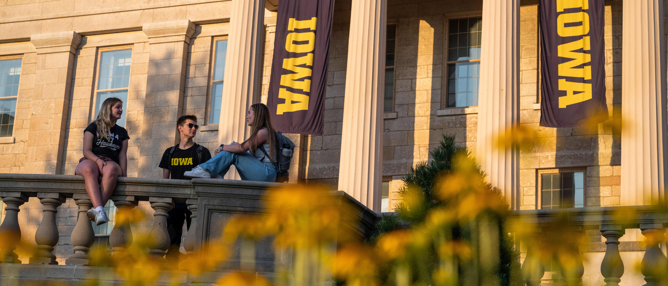 Graduates sitting and chatting on front steps of Old Cap